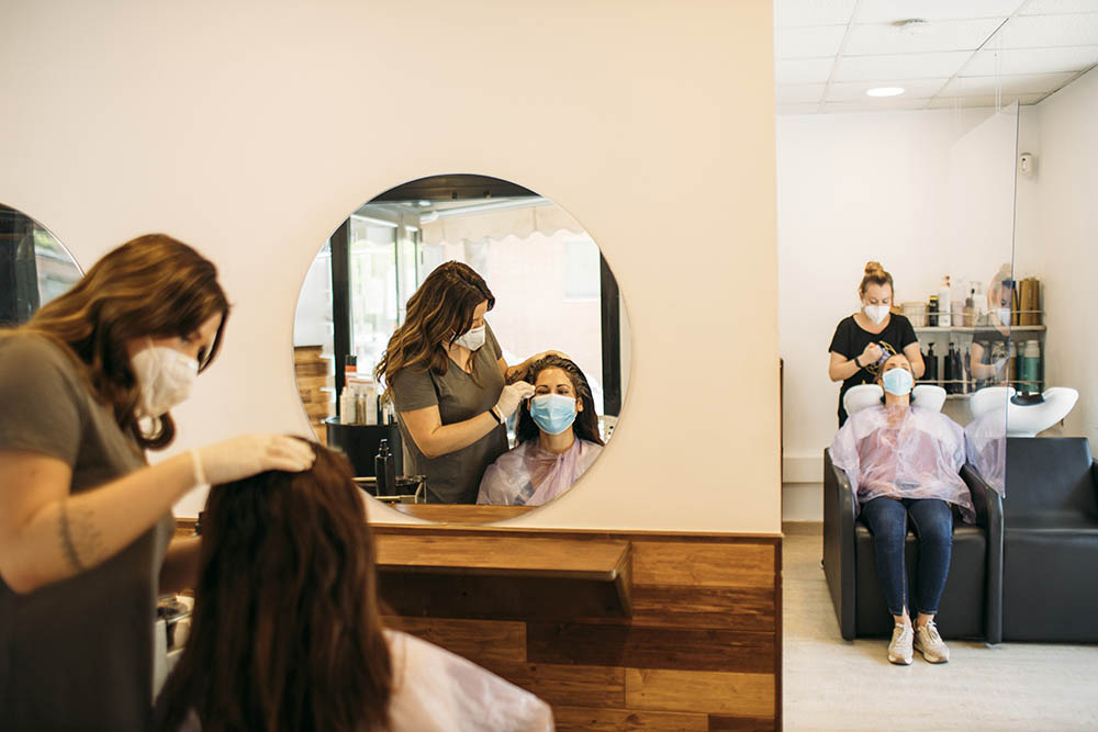 women wearing masks in a hair salon with customers wearing masks
